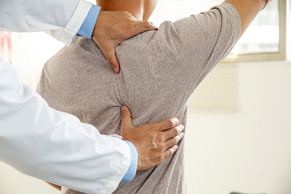 A chiropractor assessing a patient's shoulder and upper back